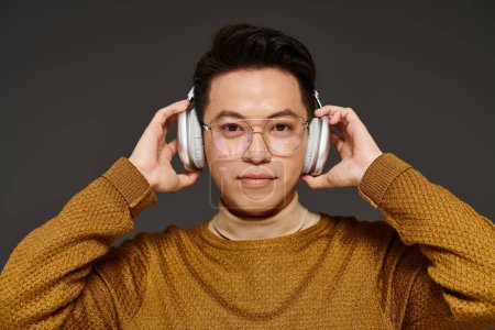 Photo for Stylish young man in elegant attire wearing glasses and headphones, immersed in music. - Royalty Free Image