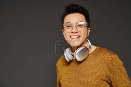 Téléchargez les photos : Un jeune homme à la mode vêtu d'un pull, écoutant activement de la musique à travers des écouteurs. - en image libre de droit