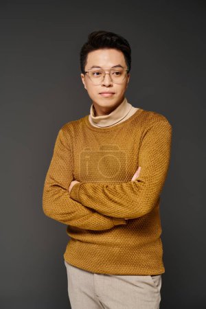 Foto de Joven de moda en gafas y suéter posando con confianza en elegante atuendo. - Imagen libre de derechos