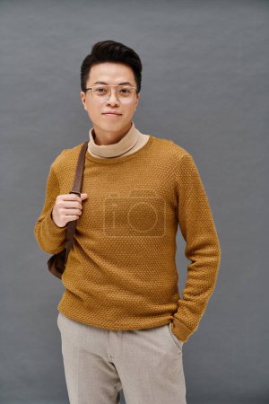 A fashionable young man poses confidently in an elegant brown sweater while holding a matching brown umbrella.