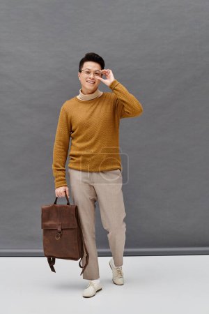 Foto de Un joven de moda con un atuendo elegante sosteniendo un maletín, exudando confianza y alegría mientras sonríe a la cámara. - Imagen libre de derechos