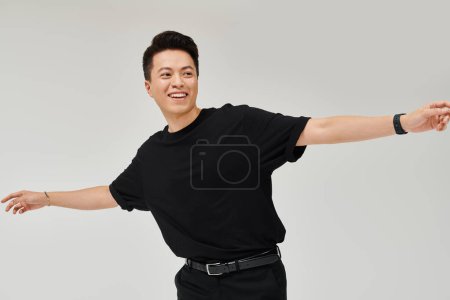 Photo for Fashionable young man in black shirt and pants strikes a dynamic pose in an elegant setting. - Royalty Free Image