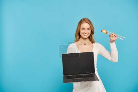Une femme blonde tenant un ordinateur portable et de la nourriture asiatique, mettant en valeur un mélange de technologie et de délices culinaires.