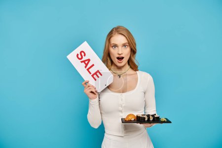 A beautiful woman with blonde hair holding a sign that says sale while posing with delicious Asian food.