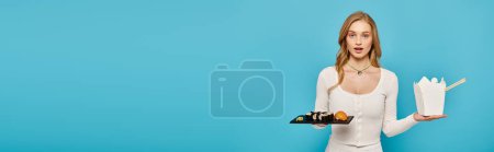 Téléchargez les photos : Une superbe femme blonde tient un plateau de plats asiatiques délicieux tout en portant une robe blanche élégante. - en image libre de droit