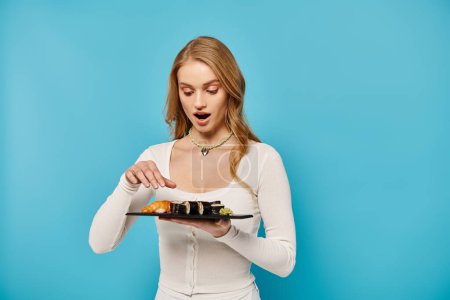 Superbe femme blonde tenant une assiette de délicieuse cuisine asiatique.