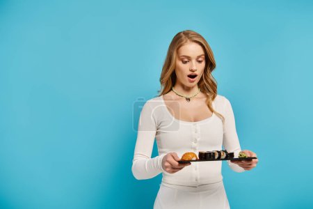 A beautiful woman in a white dress gracefully holds tray with sushi