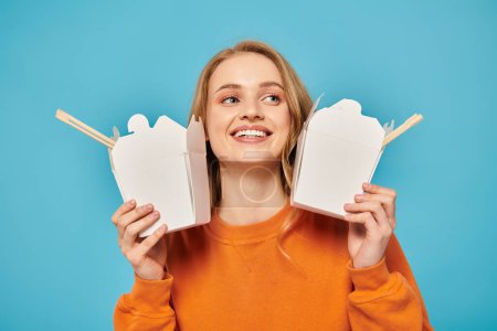 A beautiful woman holds two food boxes in front of her face, showcasing her creativity and mystery.