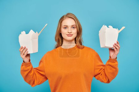 Photo for A woman holds two boxes of Asian food in front of her face - Royalty Free Image