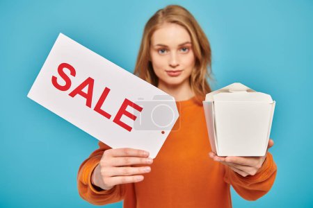 A beautiful blonde woman energetically holds a sale sign and a box of delicious Asian food while showcasing her products.