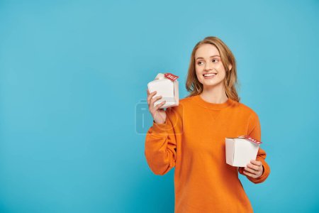 Téléchargez les photos : Une fille tient heureusement deux boîtes de nourriture asiatique dans ses mains avec étiquette de vente. - en image libre de droit