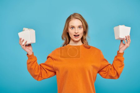 Photo for A beautiful blonde woman gracefully holds two white boxes, showcasing gourmet Asian cuisine. - Royalty Free Image