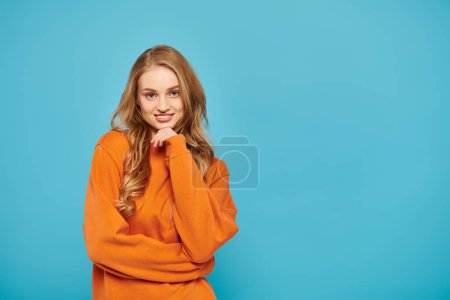 Photo for A stylish woman with blonde hair posing on bright blue backdrop. - Royalty Free Image
