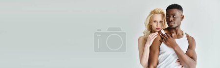 Photo for A man tenderly holds a woman in his arms, their faces close, conveying love and intimacy in a studio setting on a grey background. - Royalty Free Image