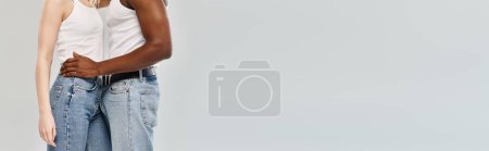 Photo for A young multicultural couple standing side by side in a studio against a grey background, showcasing unity and togetherness. - Royalty Free Image