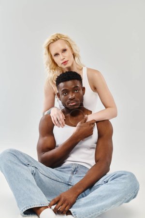 Ein Mann und eine Frau sitzen eng am Boden, ihre Körper zueinander geneigt und teilen einen Moment der Verbindung.