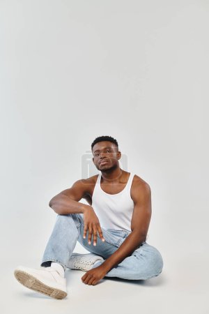 Photo for A young African American man sits cross-legged on the ground, exuding a sense of serenity and introspection. - Royalty Free Image