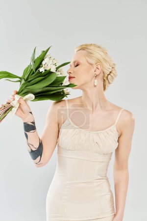Une belle mariée blonde dans une robe de mariée tenant gracieusement un bouquet de fleurs colorées.