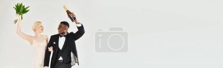 Téléchargez les photos : Un homme et une femme vêtus de tuxedos tenant des fleurs, exsudant élégance et sophistication sur un fond gris. - en image libre de droit