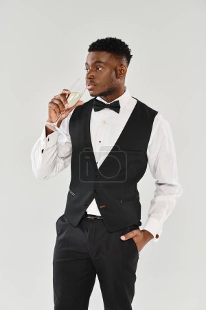 A sophisticated man in a tuxedo gracefully holds a glass of champagne, exuding elegance and charm.
