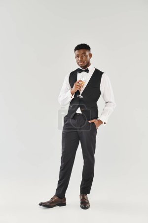 Suave man in tuxedo gracefully holds a champagne glass, radiating sophistication and charm.