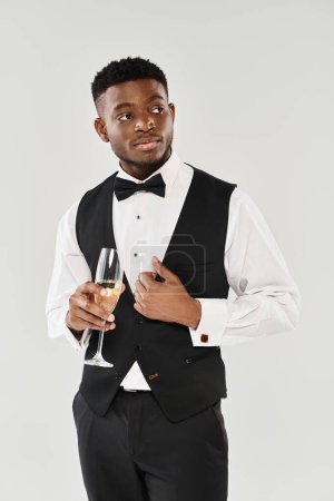 Ein Mann im Smoking strahlt Raffinesse aus, als er anmutig ein Glas Champagner in der Hand hält.