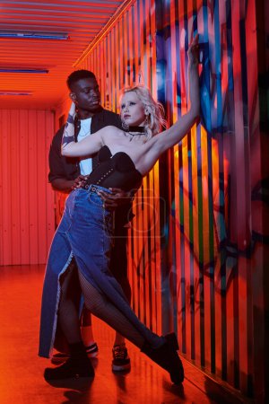 Eine blonde Frau und ein afroamerikanischer Mann tanzen anmutig in einem Raum und bewegen sich perfekt synchron zueinander.