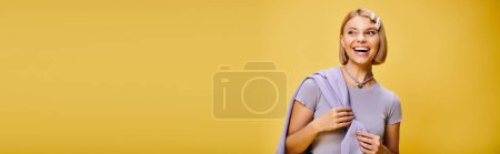 Foto de Mujer alegre bien vestida con el pelo corto rubio en traje vibrante posando sobre fondo amarillo, pancarta - Imagen libre de derechos
