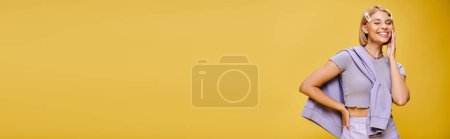 Photo for Merry well dressed woman with blonde short hair in vibrant attire posing on yellow backdrop, banner - Royalty Free Image