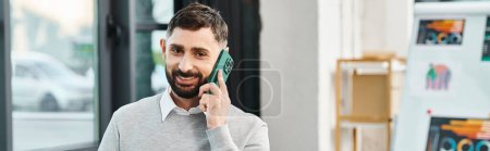 Téléchargez les photos : Un homme dans un cadre d'affaires parlant sur un téléphone portable tout en s'engageant dans un projet avec des collègues. - en image libre de droit