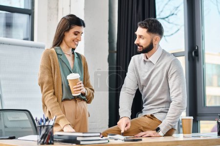 Foto de Un hombre y una mujer colaboran en un proyecto en un escritorio, tomando un descanso con el café en un entorno de oficina corporativa. - Imagen libre de derechos
