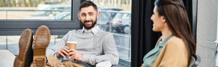 Ein Mann sitzt auf einem Stuhl und hält eine Tasse Kaffee, tief in Gedanken in einem Büro-Umfeld für Unternehmen.