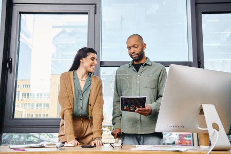 Ein Mann und eine Frau arbeiten in einem Büro zusammen, stehen vor einem Computer und arbeiten gemeinsam an einem Geschäftsprojekt.