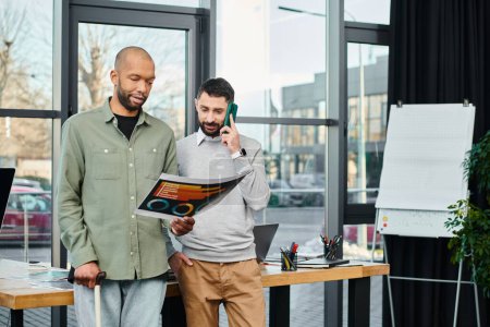 Foto de Dos hombres de negocios de pie uno al lado del otro en un entorno de oficina, discutiendo un proyecto. - Imagen libre de derechos