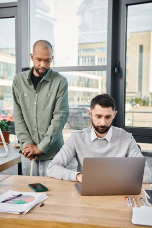 Zwei Geschäftsleute in einem Büro, das sich mit einem Laptop beschäftigt, ihr Gesicht nachdenklich und konzentriert, inmitten einer produktiven Arbeitssitzung.