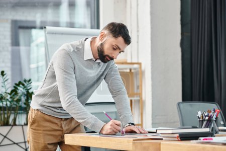 Un hombre parado en un escritorio, enfocado, escribiendo en un pedazo de papel con determinación mientras trabaja en un proyecto en una oficina corporativa.