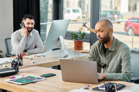 Deux professionnels des affaires sont assis à une table dans un bureau travaillant sur leurs ordinateurs portables, concentrés et engagés dans leur projet.