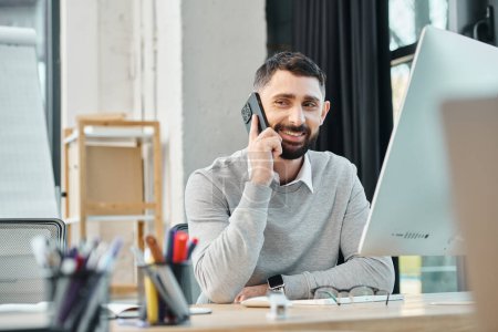 Foto de Un hombre absorto en una llamada mientras está sentado en su escritorio en un entorno de oficina, parte de un equipo centrado en un proyecto. - Imagen libre de derechos