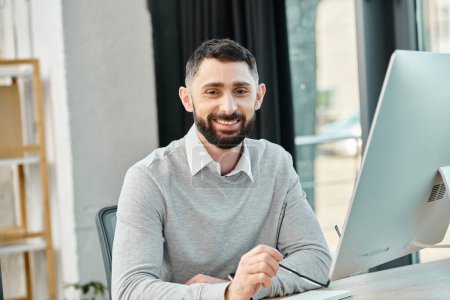 Ein Mann, der sich auf seinen Computerbildschirm konzentriert, während er an einem Schreibtisch in einem geschäftigen Büro sitzt und in die Unternehmenskultur eintaucht.