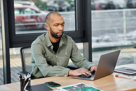 Un hombre con síndrome de miastenia grave inmerso en el trabajo, sentado en una mesa y utilizando un ordenador portátil en un entorno de oficina ocupado.