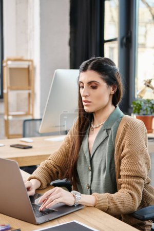 A woman focused on her laptop, deeply engaged in office work at a desk in a corporate setting.