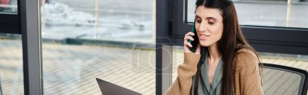 Photo for A woman engaged in a conversation on a cell phone while sitting at a table in a business setting. - Royalty Free Image