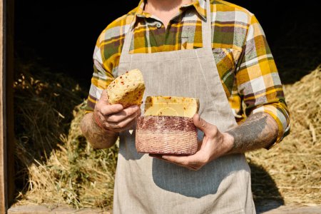 Foto de Vista recortada de agricultor adulto con tatuajes en atuendo casual sosteniendo queso casero en las manos - Imagen libre de derechos