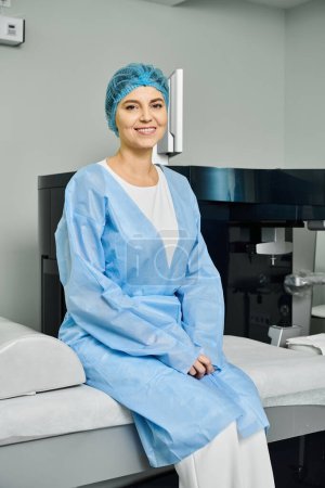 Une femme en robe d'hôpital assise paisiblement sur un lit.
