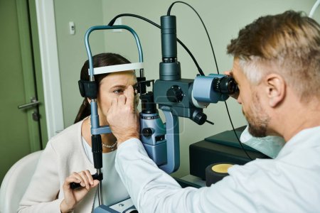 Un hombre estudia a una mujer a través de sus herramientas en una oficina de médicos para la corrección de la visión láser.