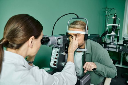 Atractivo médico examinando un ojo de hombre en un entorno profesional.