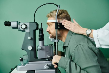 Photo for Hard working doctor examines mans eyes through a microscope in a doctors office for laser vision correction. - Royalty Free Image