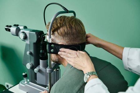 Doctor with wristwatch examines mans eyes in a doctors office for laser vision correction.