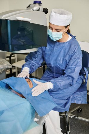 Una mujer con una bata de hospital opera una máquina para la corrección de la visión láser.