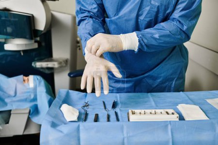 Téléchargez les photos : Un homme en robe médicale portant soigneusement des gants. - en image libre de droit